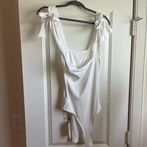 White bodysuit with bow-tie shoulder straps.